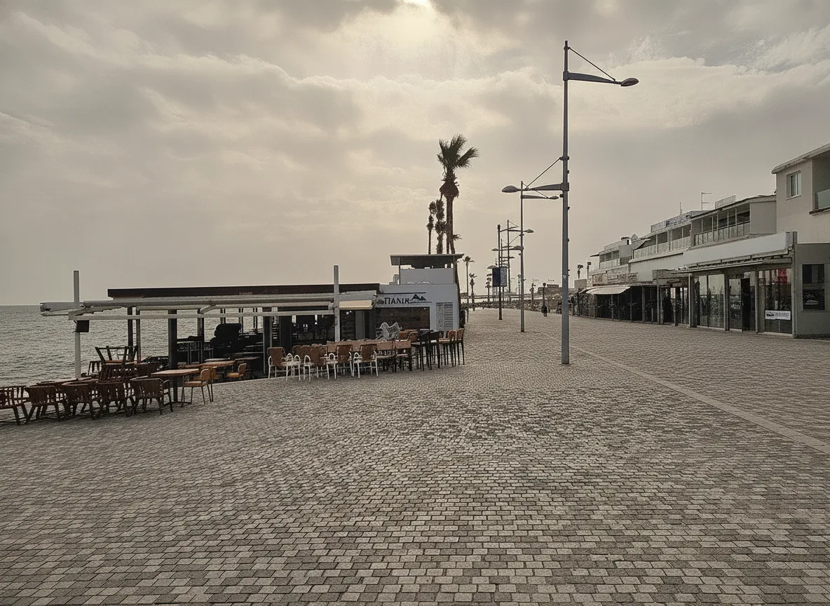 Empty Kato Paphos seafront promenade with restaurant terraces in off-season morning light
