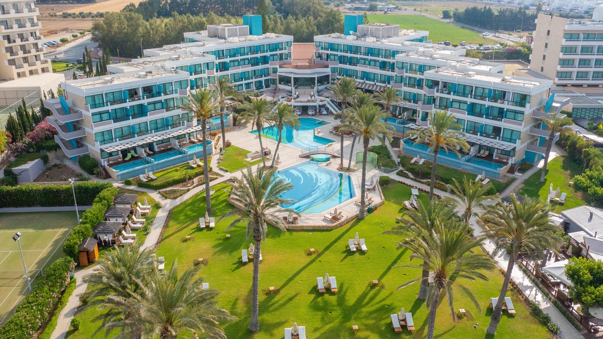 Aerial twilight view of a clifftop boutique hotel with an infinity pool in Cyprus
